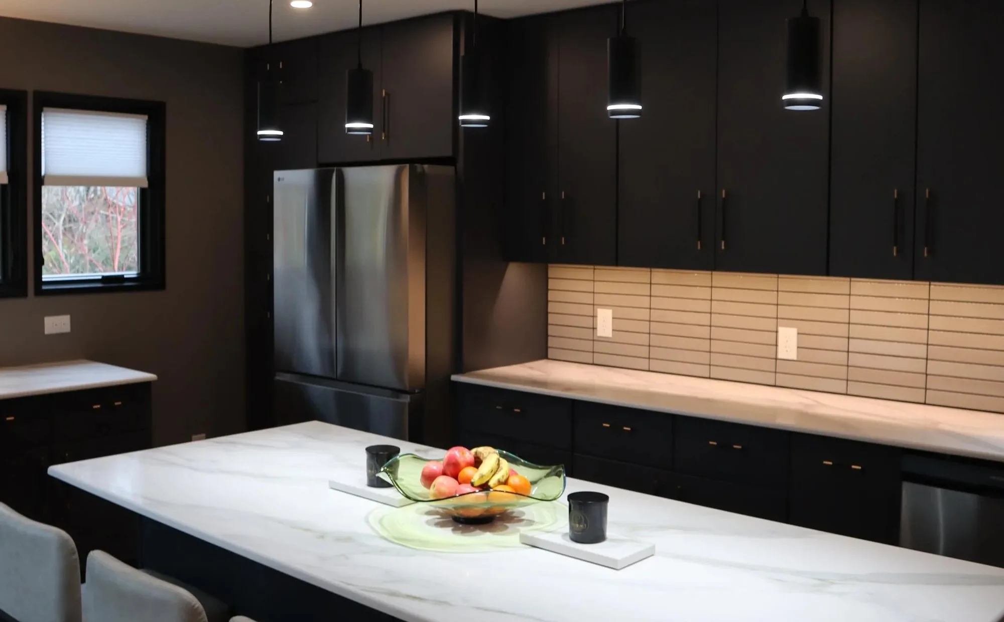 A kitchen remodeled by Bottom Line Renovations, with dark cabinetry and a marble island