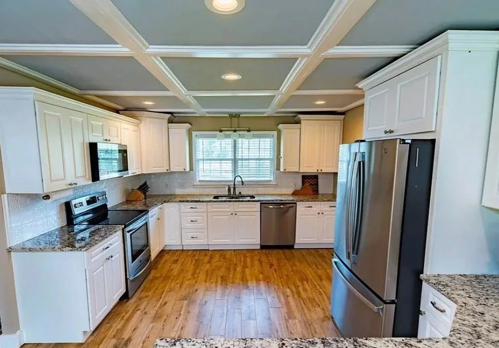 White shaker kitchen with a coffered ceiling and granite counters