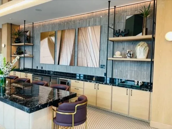 Home lounge with a stone bar top, backlit shelving and upholstered stools